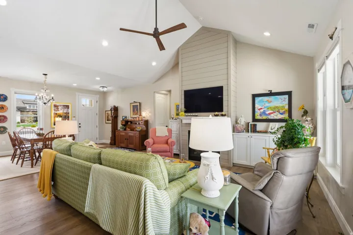 Living area featuring wood finished floors, ceiling fan, a high ceiling, and a chandelier