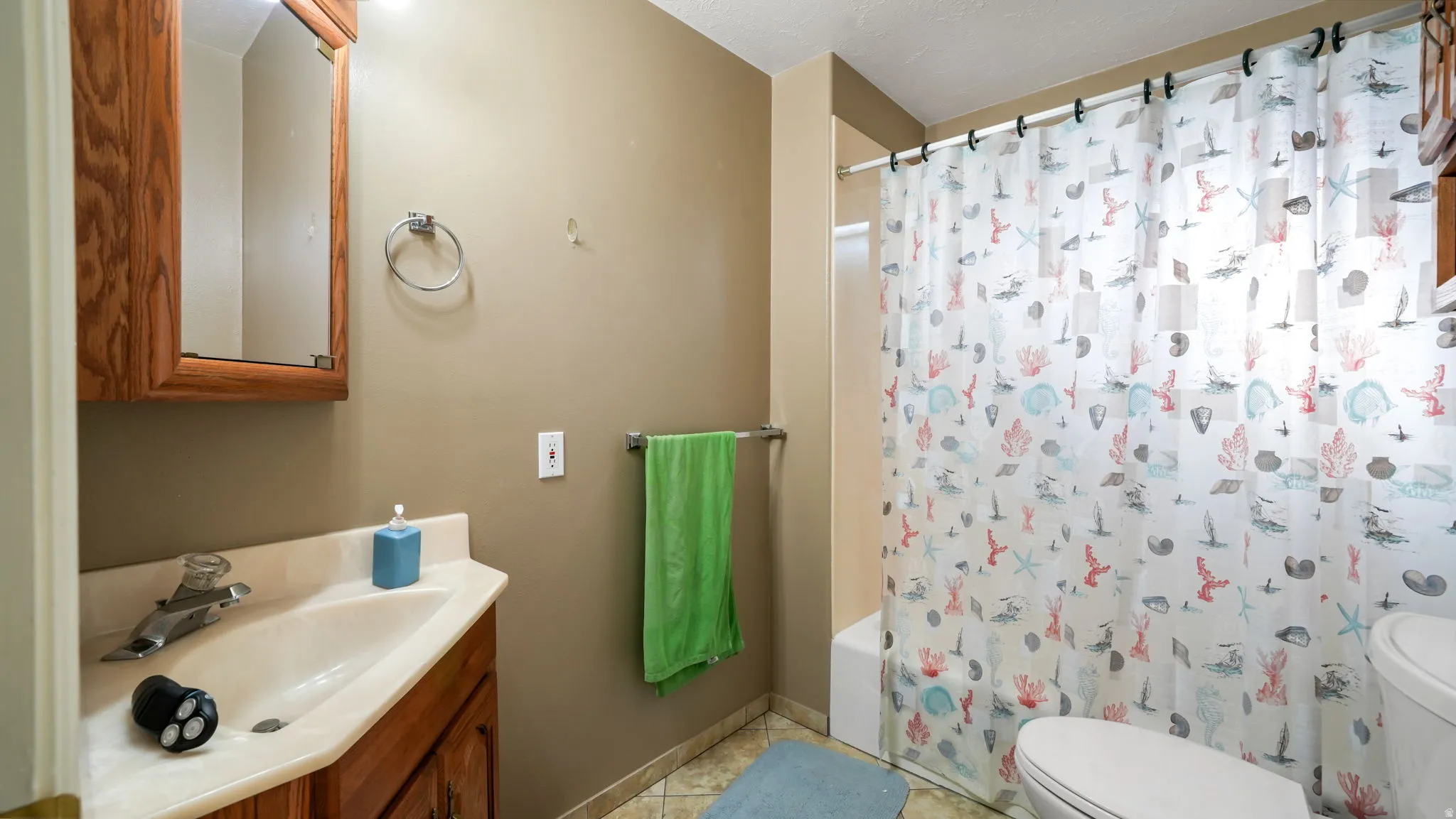 Bathroom featuring vanity, shower / bathtub combination with curtain, and light tile patterned floors