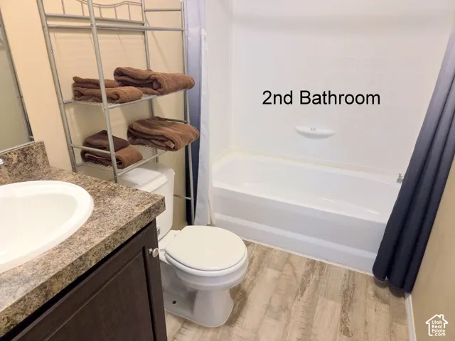 Full bathroom with vanity, light wood-style flooring, and shower / tub combo