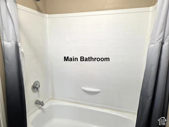 White tile-patterned shower surround with a built-in shelf and chrome fixtures