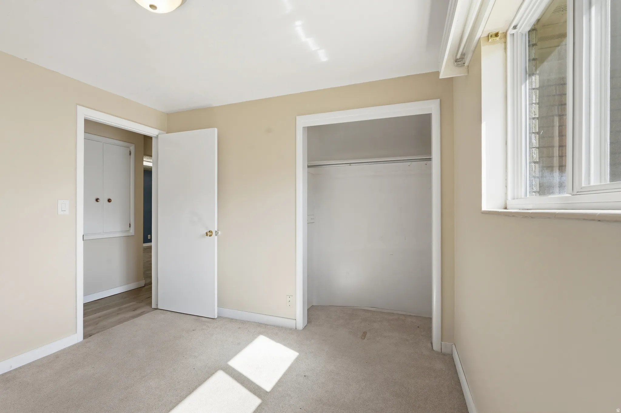 Unfurnished bedroom with light colored carpet and a closet