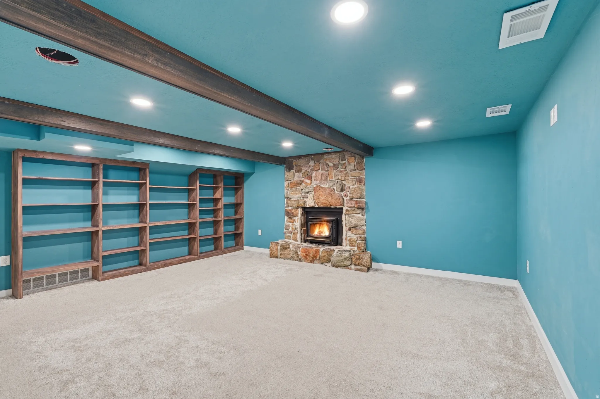 Unfurnished living room with beamed ceiling, carpet, a fireplace, and recessed lighting