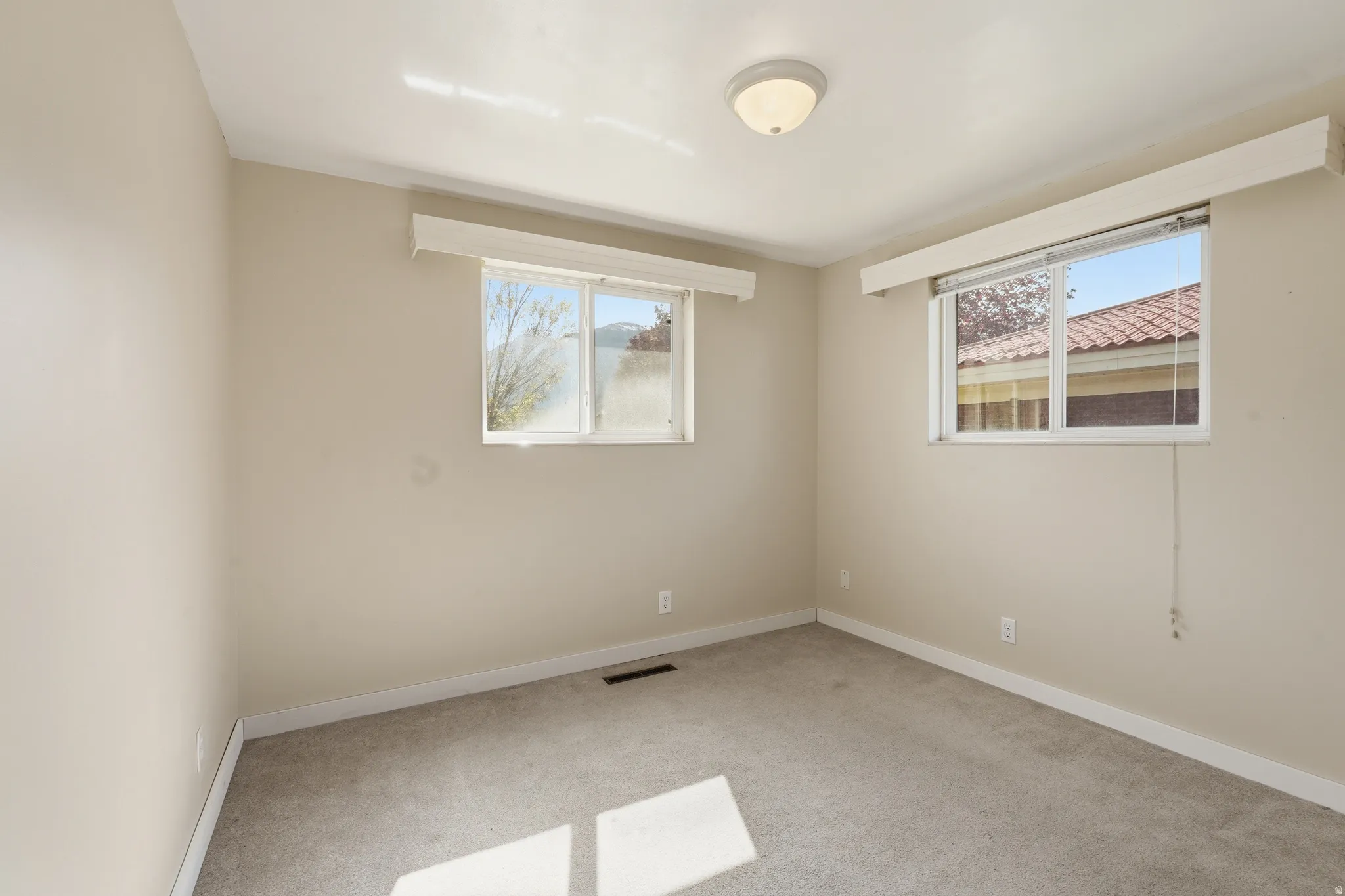 Unfurnished room featuring light carpet and baseboards