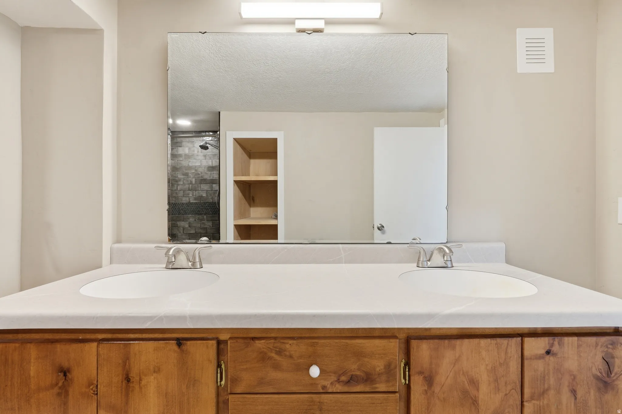 Full bathroom with double vanity and tiled shower