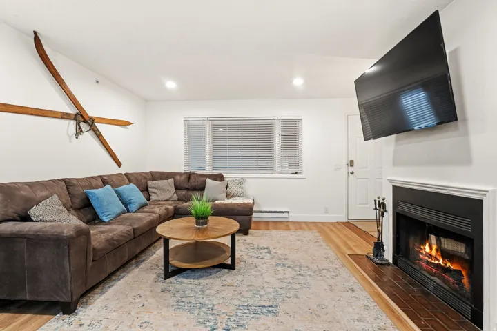 Living area featuring light wood finished floors, a fireplace with flush hearth, baseboard heating, and recessed lighting