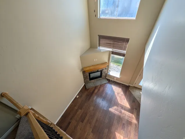 Unfurnished living room featuring a stone fireplace, dark wood finished floors, and a high ceiling