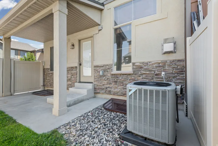Covered patio with stone accent wall featuring mixed-tone stacked stone veneer, concrete flooring, and white columns