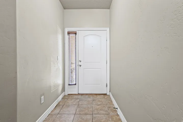 Entryway featuring a white paneled door with a side light, complemented by horizontal blinds