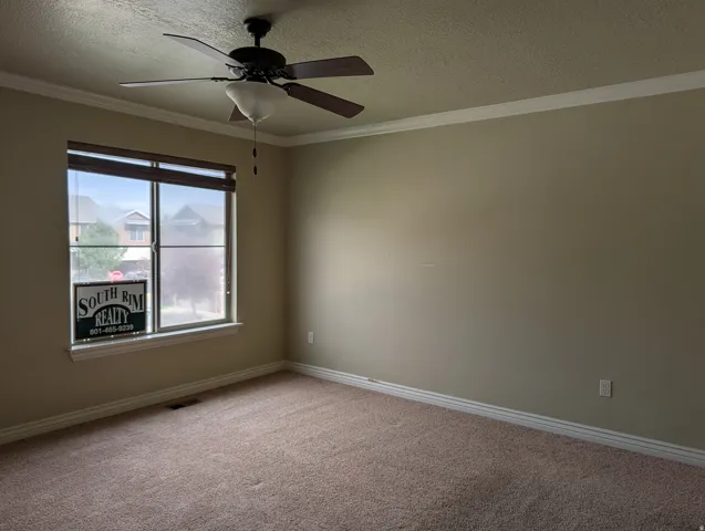 Recessed window with blinds, ceiling fan with light fixture, wall-to-wall carpeting, and crown molding