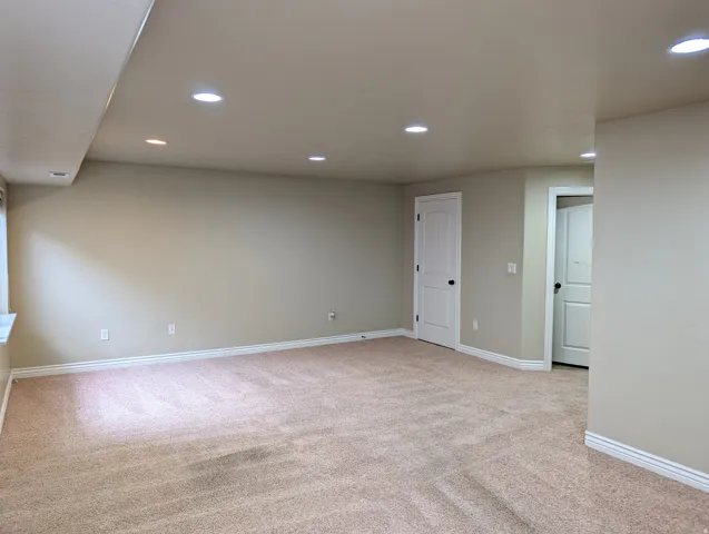 Spacious room featuring neutral carpet flooring, recessed lighting, and white trim
