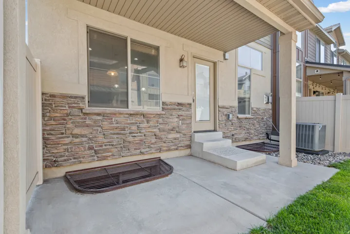 Covered patio with decorative brick accents, concrete flooring, and direct access to the home through sliding glass doors and entry door