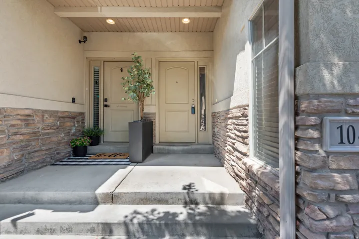 Concrete entryway with stone veneer accents and stucco siding