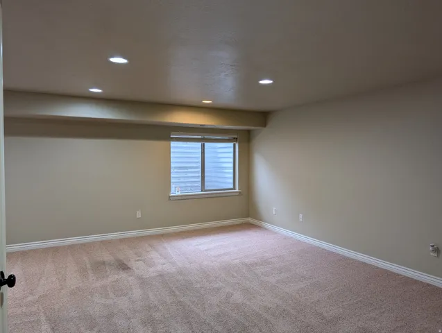 Recessed lighting, neutral wall tones, window with blinds, light-colored carpeting, and white trim