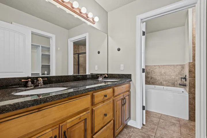 Double vanity with dark granite countertop and light wood cabinetry