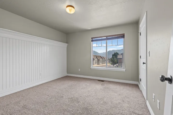 Room with carpet flooring, beadboard wainscoting, and a window with mountain scenery