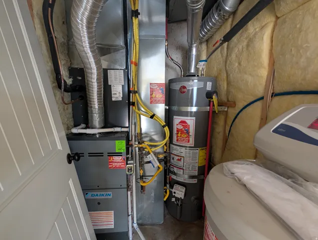 Utility room featuring water heater and heating unit