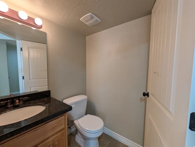 Half bath featuring vanity, a textured ceiling, and dark tile patterned floors