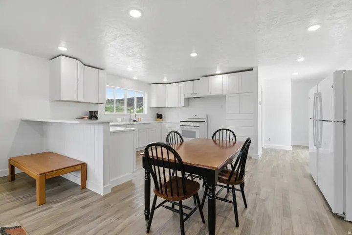 Dining room with a textured ceiling, light wood-style floors, and recessed lighting
