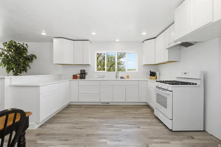 Kitchen with gas range gas stove, white cabinetry, light wood-style floors, and recessed lighting