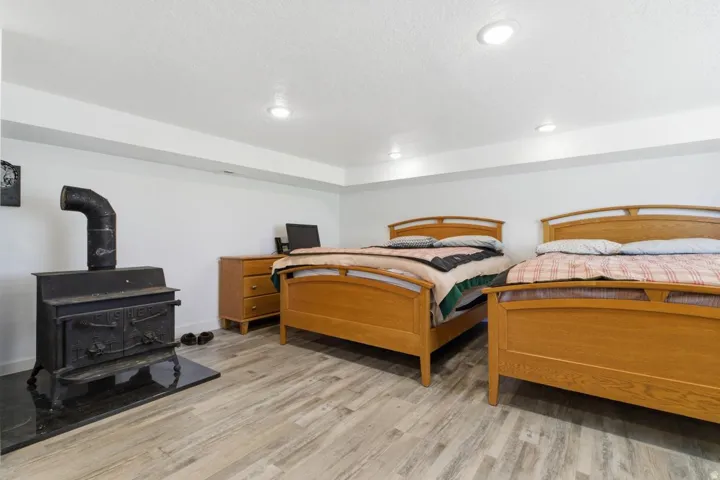 Bedroom featuring light wood-style floors, a wood stove, recessed lighting, and a textured ceiling