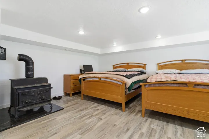 Bedroom featuring light wood-style floors, a wood stove, recessed lighting, and a textured ceiling