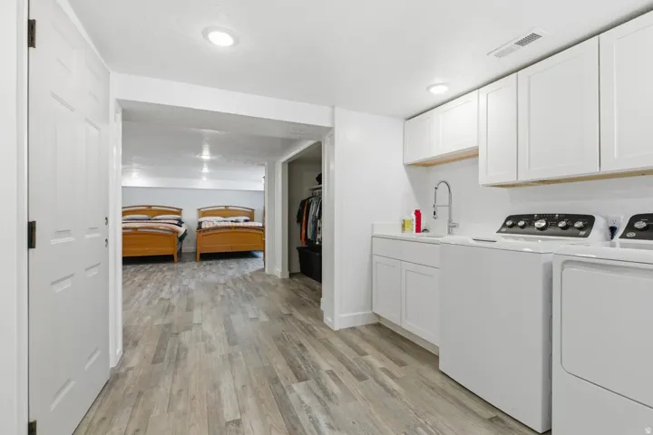 Laundry area featuring washer and dryer, light wood-style flooring, cabinet space, and recessed lighting