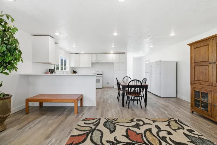 Kitchen with white appliances, a peninsula, light countertops, light wood-style floors, and white cabinets