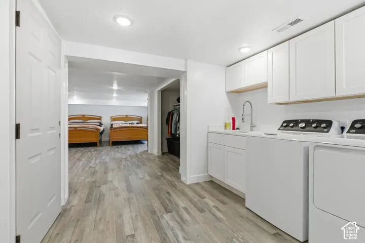 Laundry area featuring washer and dryer, light wood-style flooring, cabinet space, and recessed lighting