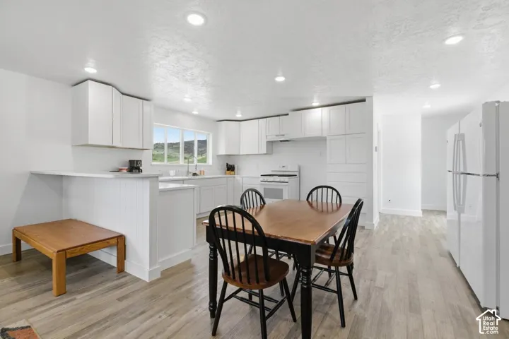 Dining room with a textured ceiling, light wood-style floors, and recessed lighting