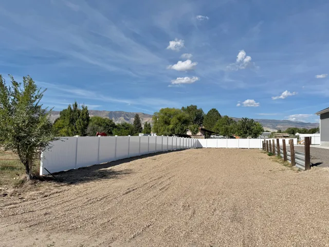 Graded lot with a white privacy fence and partial wood fence