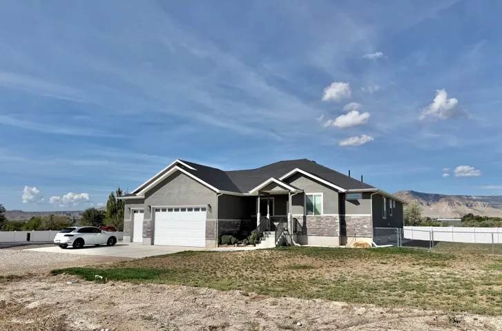 Contemporary exterior featuring stucco and stone accents, a multi-car garage, and a covered porch