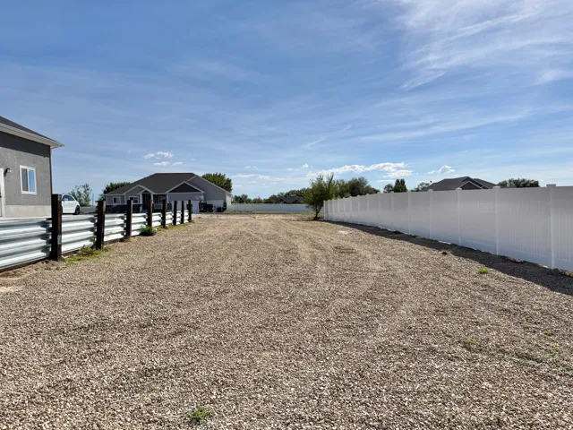 Gravel-covered expanse with a full-length white privacy fence