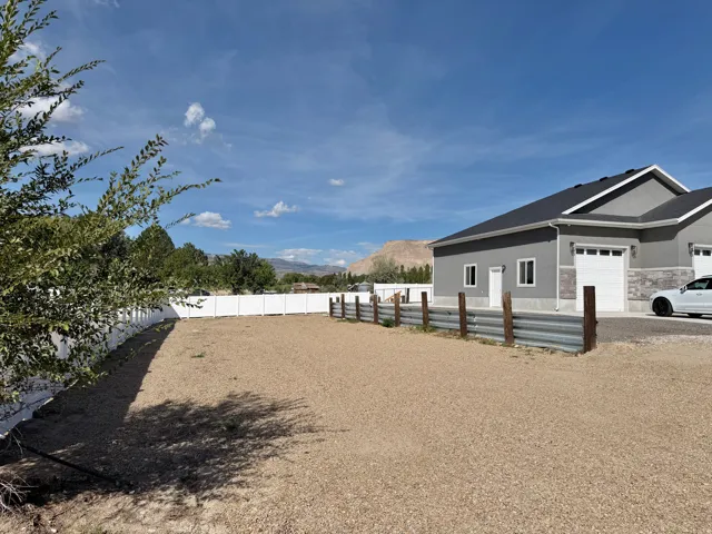 Gravel lot with perimeter fencing, featuring a white vinyl fence and a corrugated metal fence