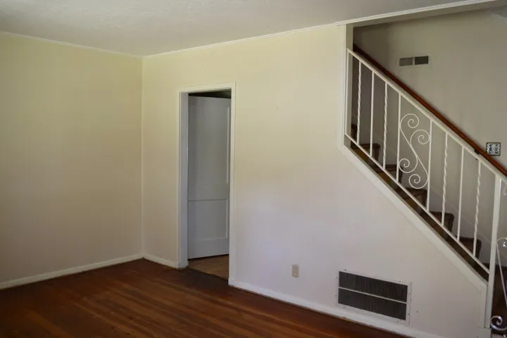 Unfurnished living room featuring dark wood-style floors and ornamental molding