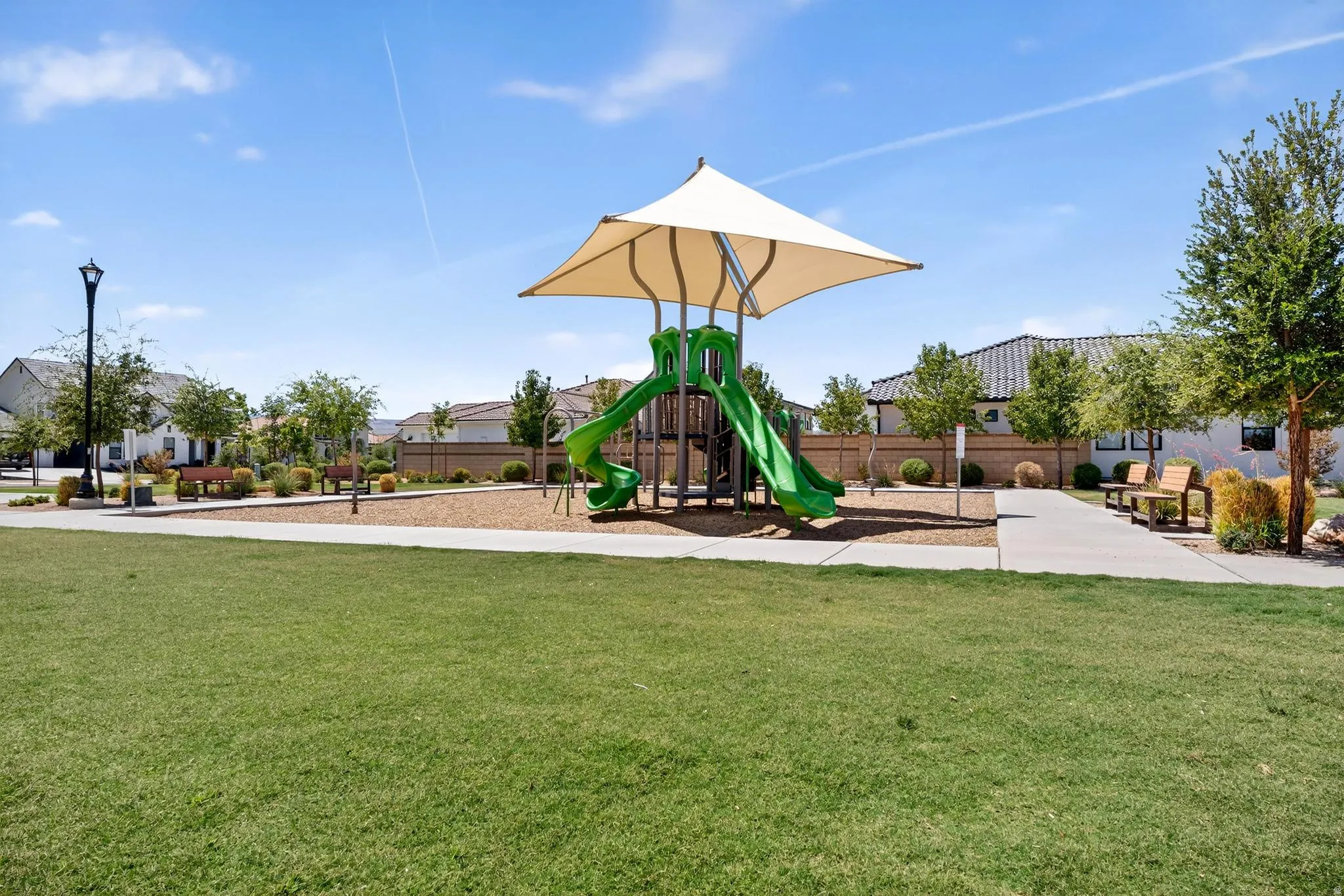 Community green space featuring a playground with slides and a shade canopy