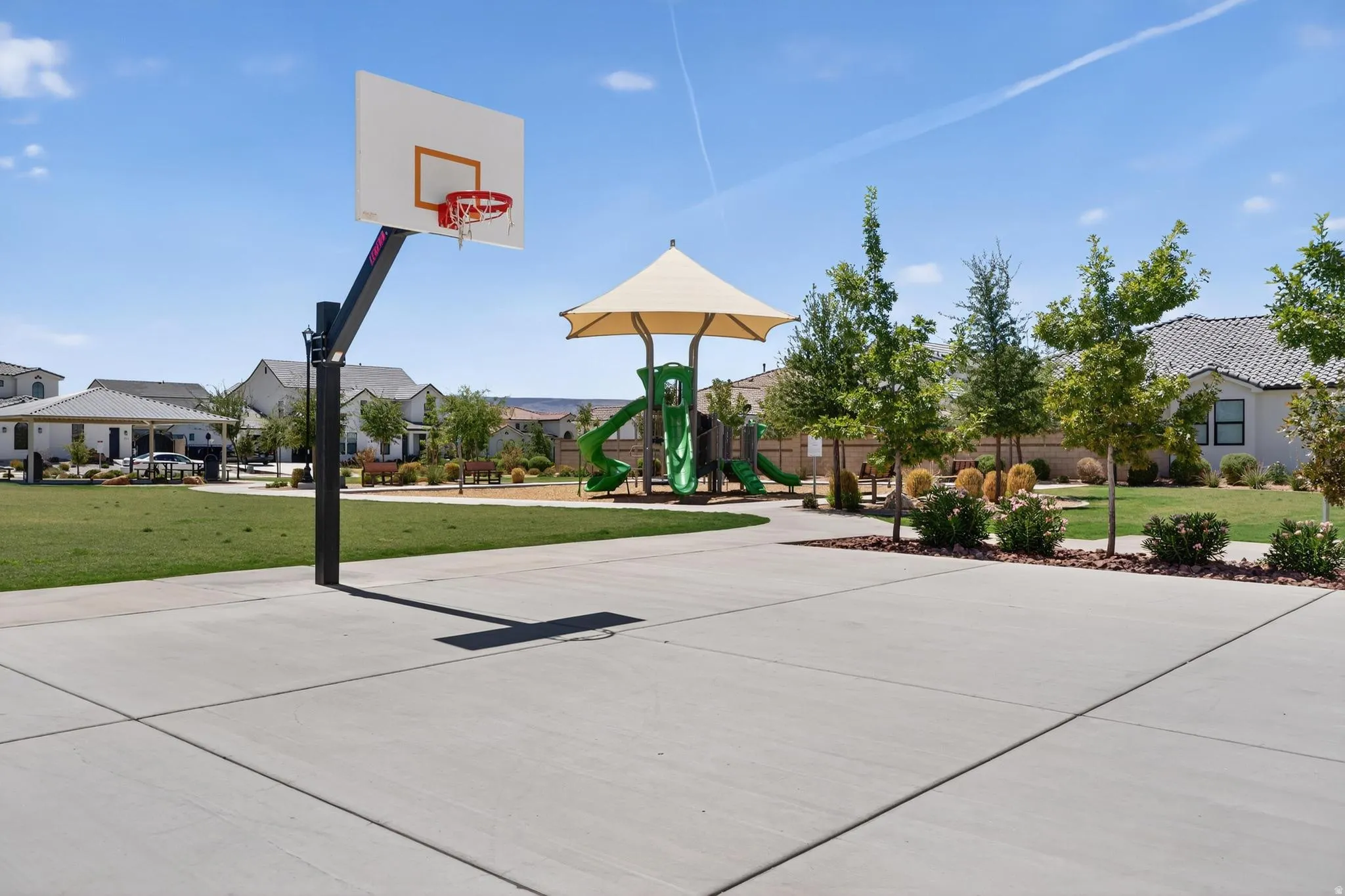 Concrete basketball court featuring a backboard and hoop