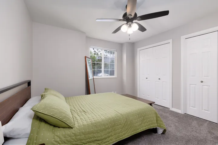 Bedroom featuring two closets, carpet, and ceiling fan