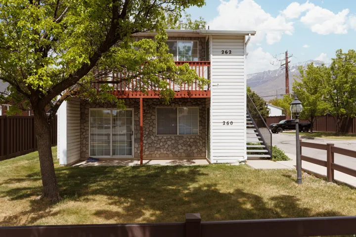 Rear view of property featuring stone siding and a balcony