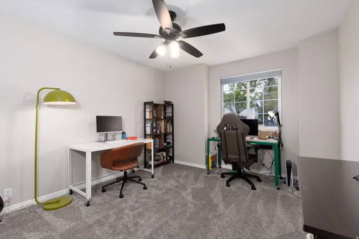 Carpeted home office with ceiling fan and baseboards