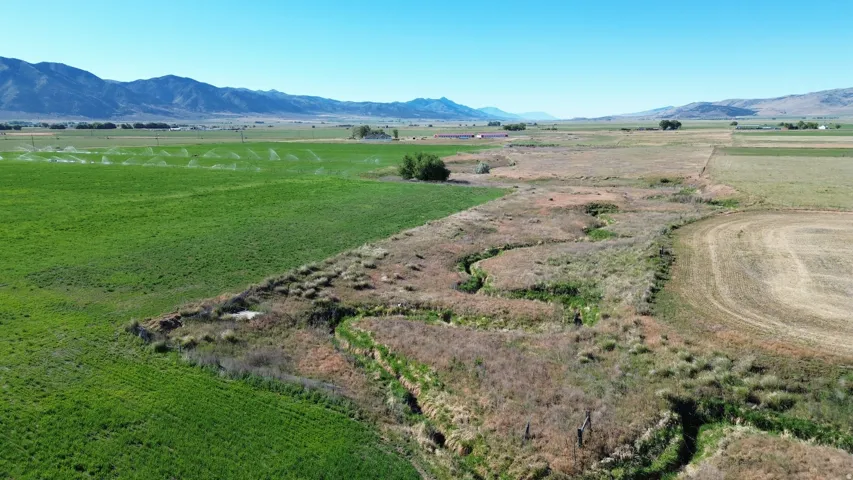 Expansive agricultural land featuring a verdant field, a harvested field, and a winding natural waterway