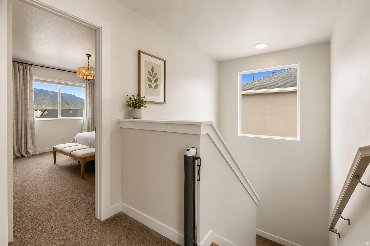 Carpeted hallway and bedroom featuring mountain scenery through a large window, a modern pendant light fixture, and a built-in wall niche