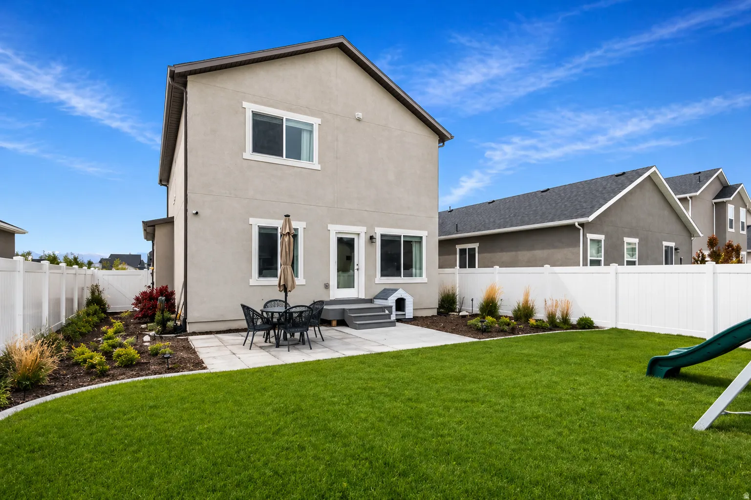 Back of property with a patio area, stucco siding, a fenced backyard, and a playground