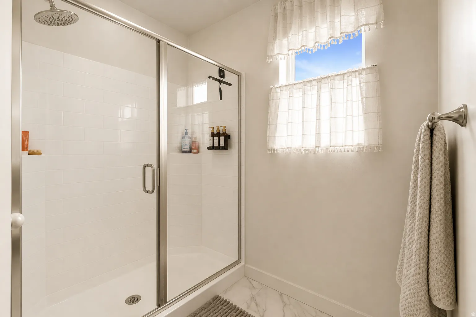 Walk-in shower with a glass enclosure, white tile surround, and an overhead rain shower head