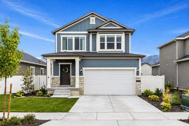 Craftsman-style house with an attached garage, board and batten siding, concrete driveway, and stone siding