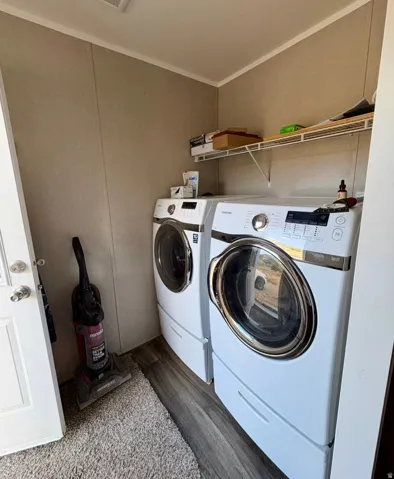 Laundry area with dark wood-style floors, separate washer and dryer, and crown molding