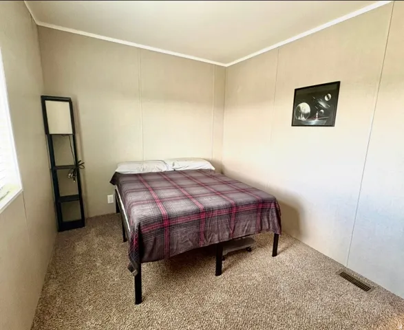 Bedroom featuring carpet and a decorative wall