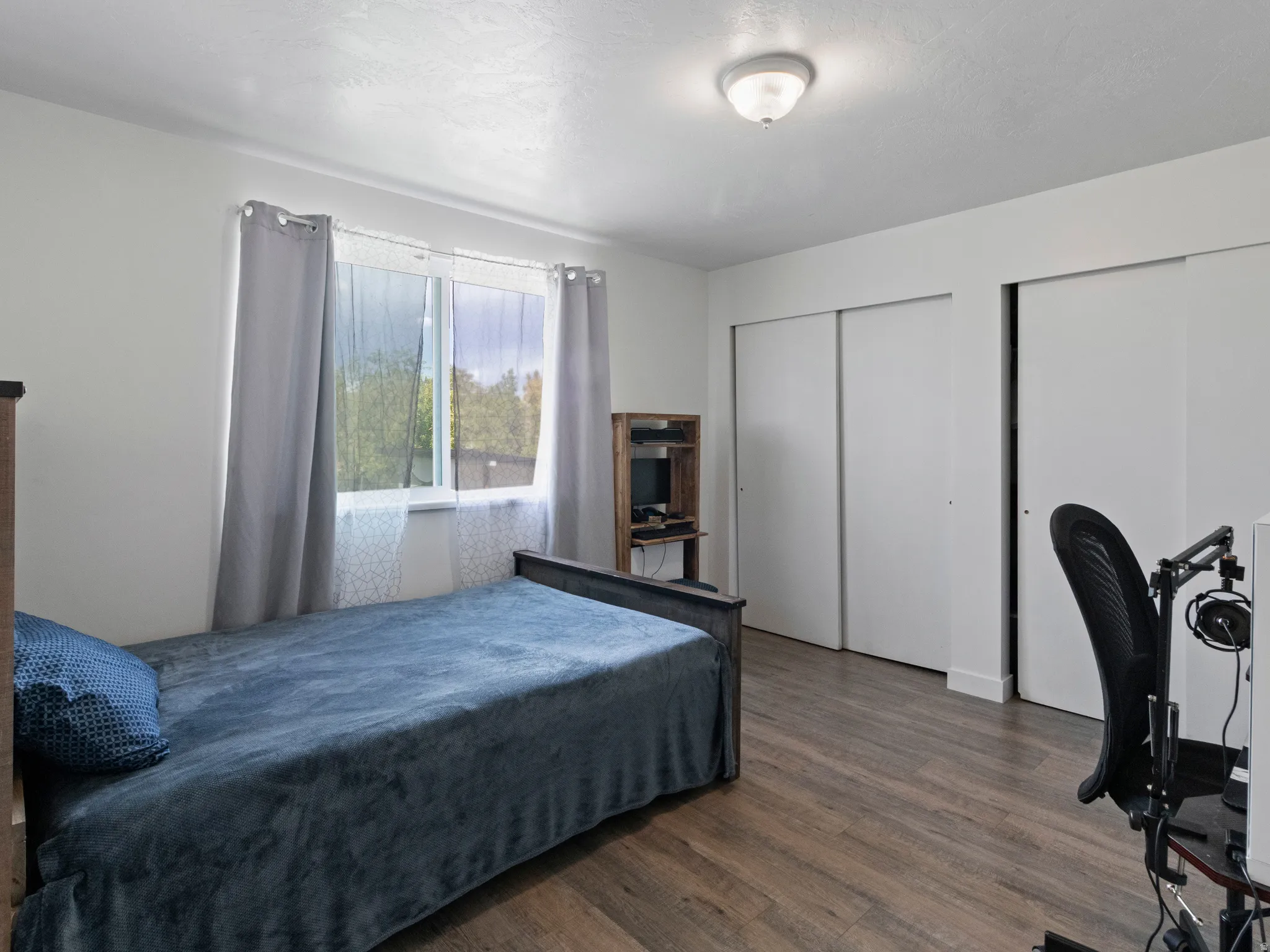 Bedroom with two closets and dark wood-style floors