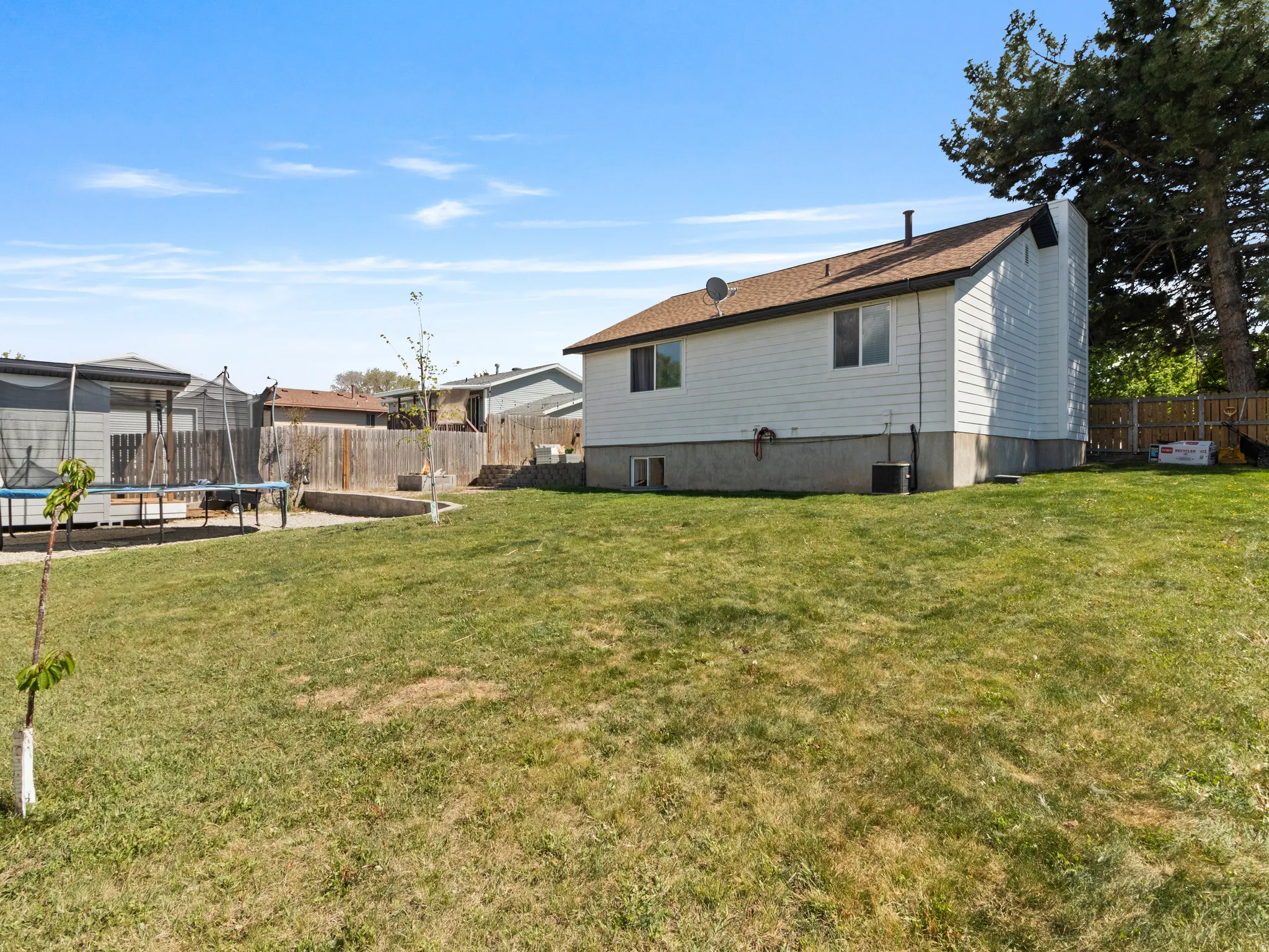 Back of house with a trampoline, a fenced backyard, and a chimney