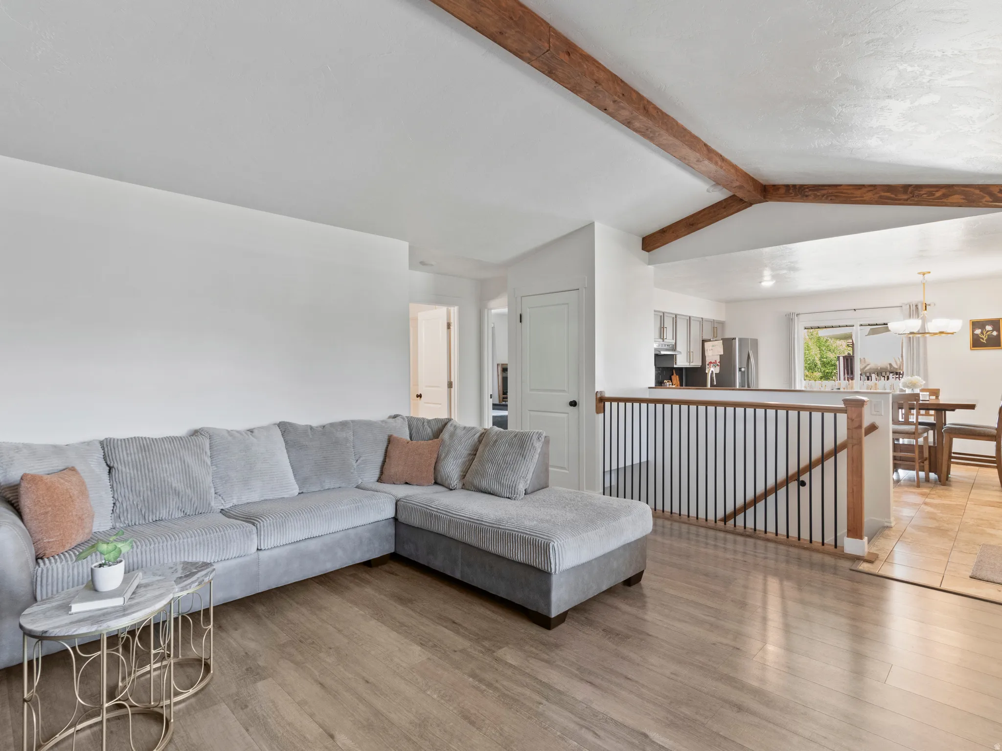 Living area with light wood-style flooring, beamed ceiling, and a chandelier