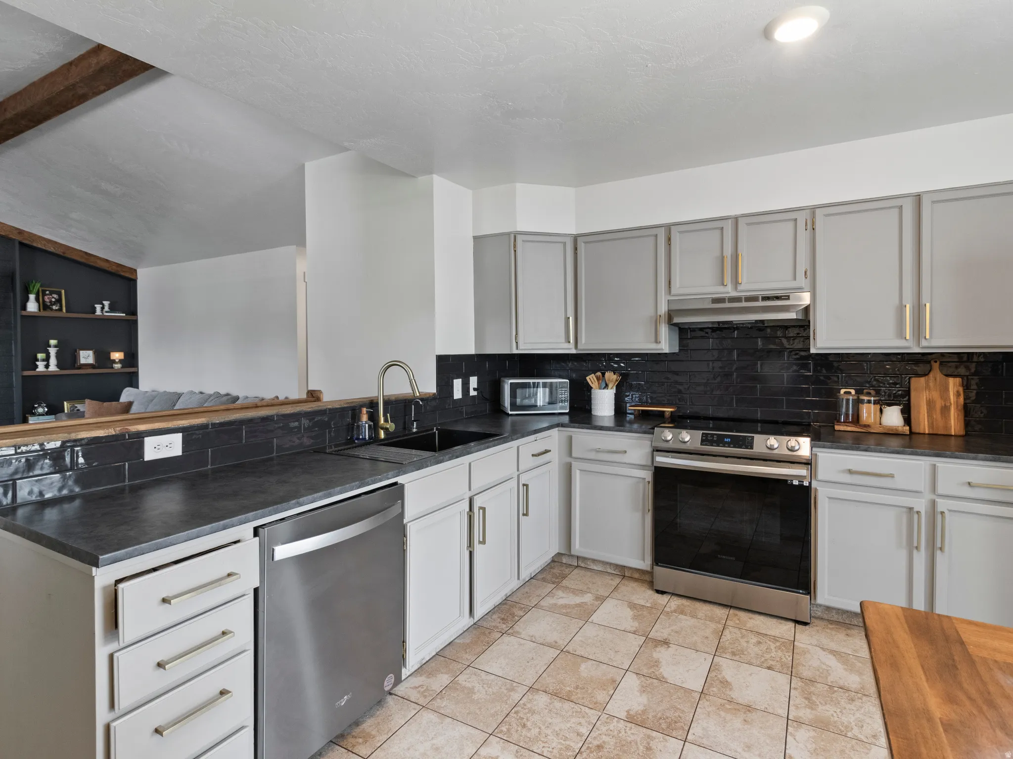Kitchen featuring stainless steel appliances, tasteful backsplash, gray cabinets, light tile patterned floors, and a peninsula